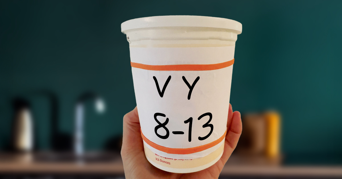 Hand holding large yogurt container with a large print label: V-Y and 8-13