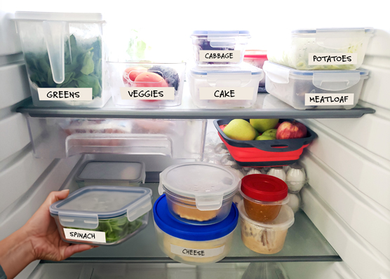 Inside a well-organized refrigerator, with containers and bins marked in large print.