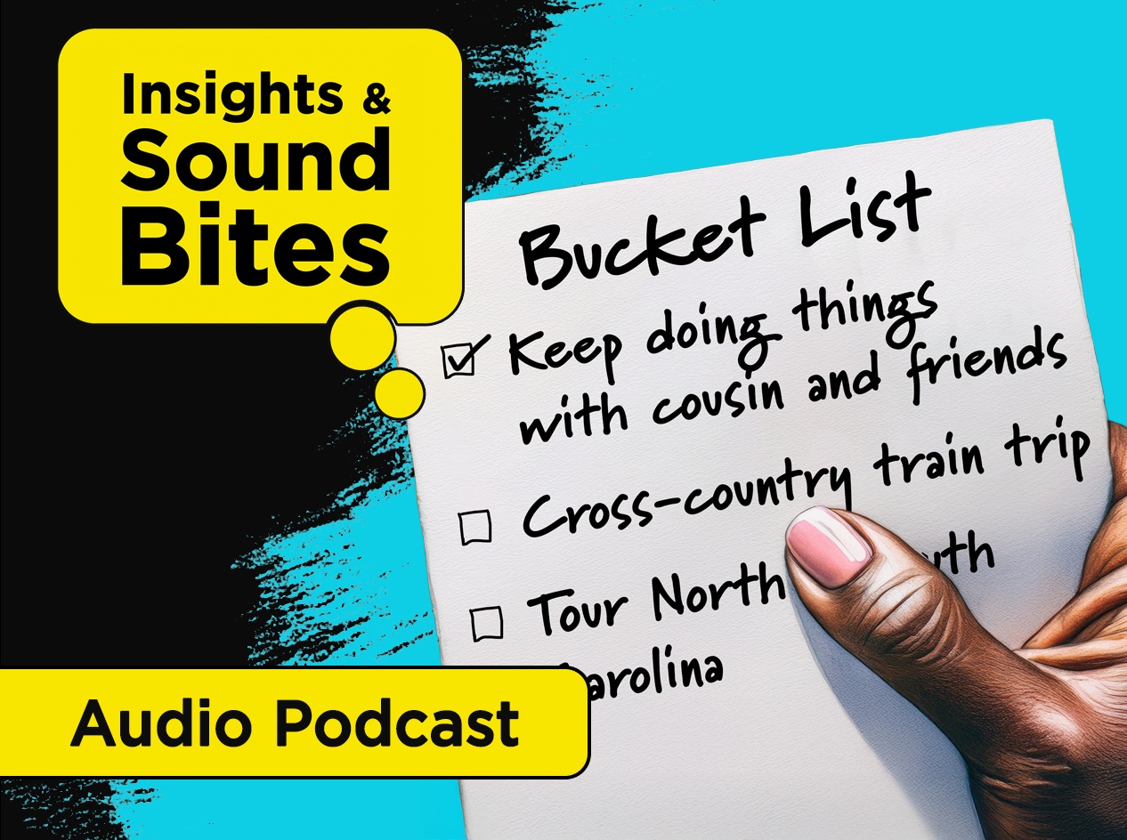 Close-up of hand holding paper with hand-written bucket list checklist. Keep doing things with cousin and friends is checked. Other unchecked items are: Cross-country train trip and Tour North & South Carolina.