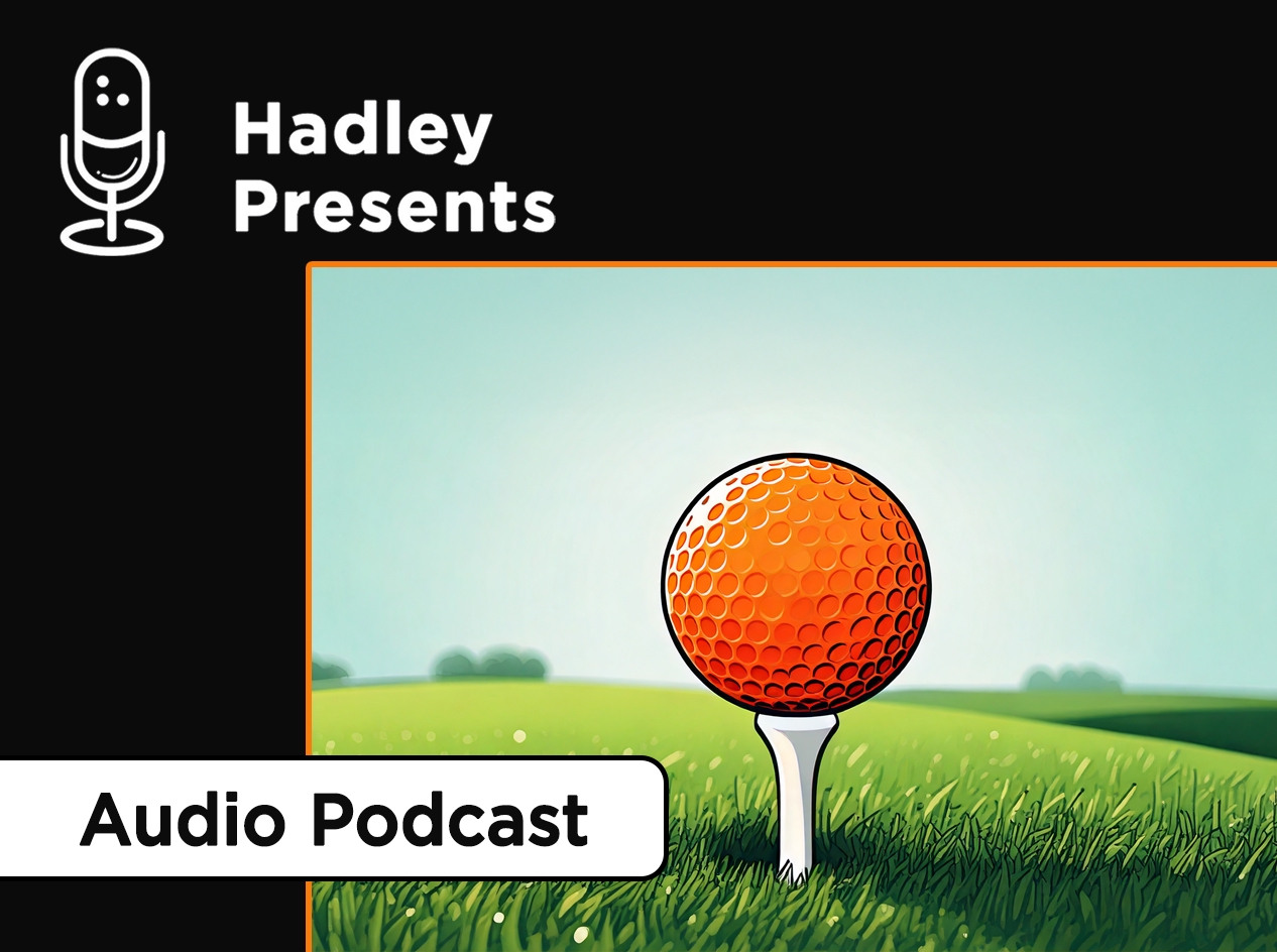 Close-up of orange golf ball on a white tee in bright green golf course grass.