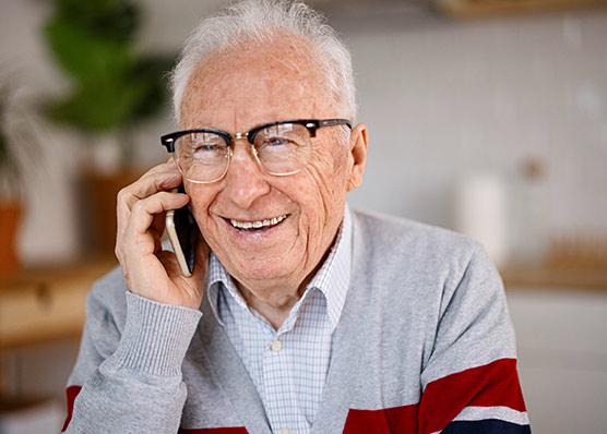 An older adult speaking on the phone, representing peer-to-peer support and connection