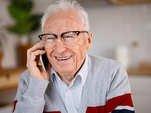 An older adult speaking on the phone, representing peer-to-peer support and connection